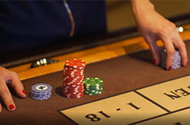 Player Hands with Casino Chips on a Roulette Table