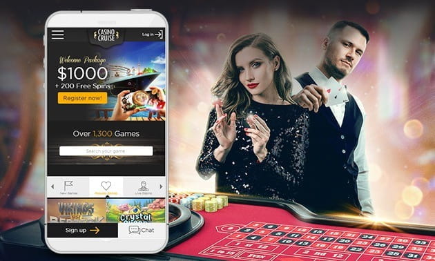Two dealers standing next to a smartphone which displays the Casino Cruise mobile site.