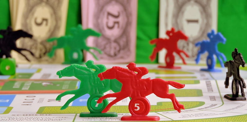 Two Horse Figures on a Track of a Board Game Involving Betting 
