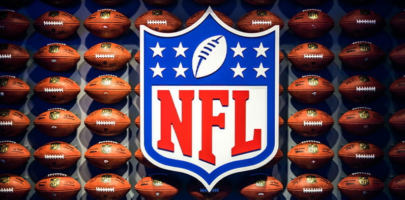 Das NFL-Logo vor einer Mauer aus American Football-Bällen 