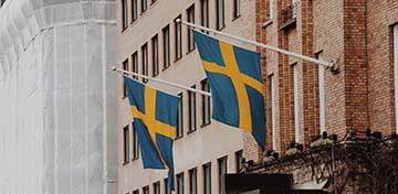 Two Flags of Sweden Hanging On a Building
