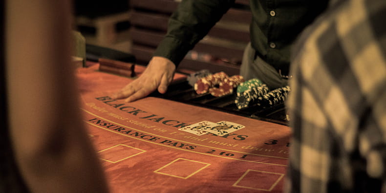 Seorang pria membagikan kartu di meja blackjack 