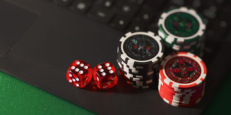 Casino Chips and Dice Placed over a Laptop