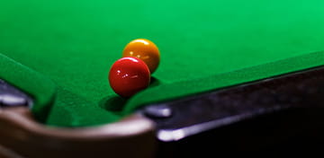 Yellow and Red Snooker Balls Touching Next to a Pocket